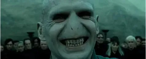 Close-up of pale, grinning, bald figure in dark, misty setting.